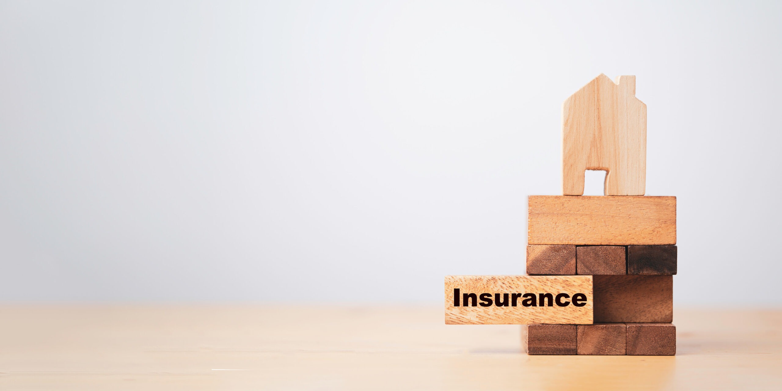 A small wooden house sits on top of stacked wooden blocks, with one block labeled 